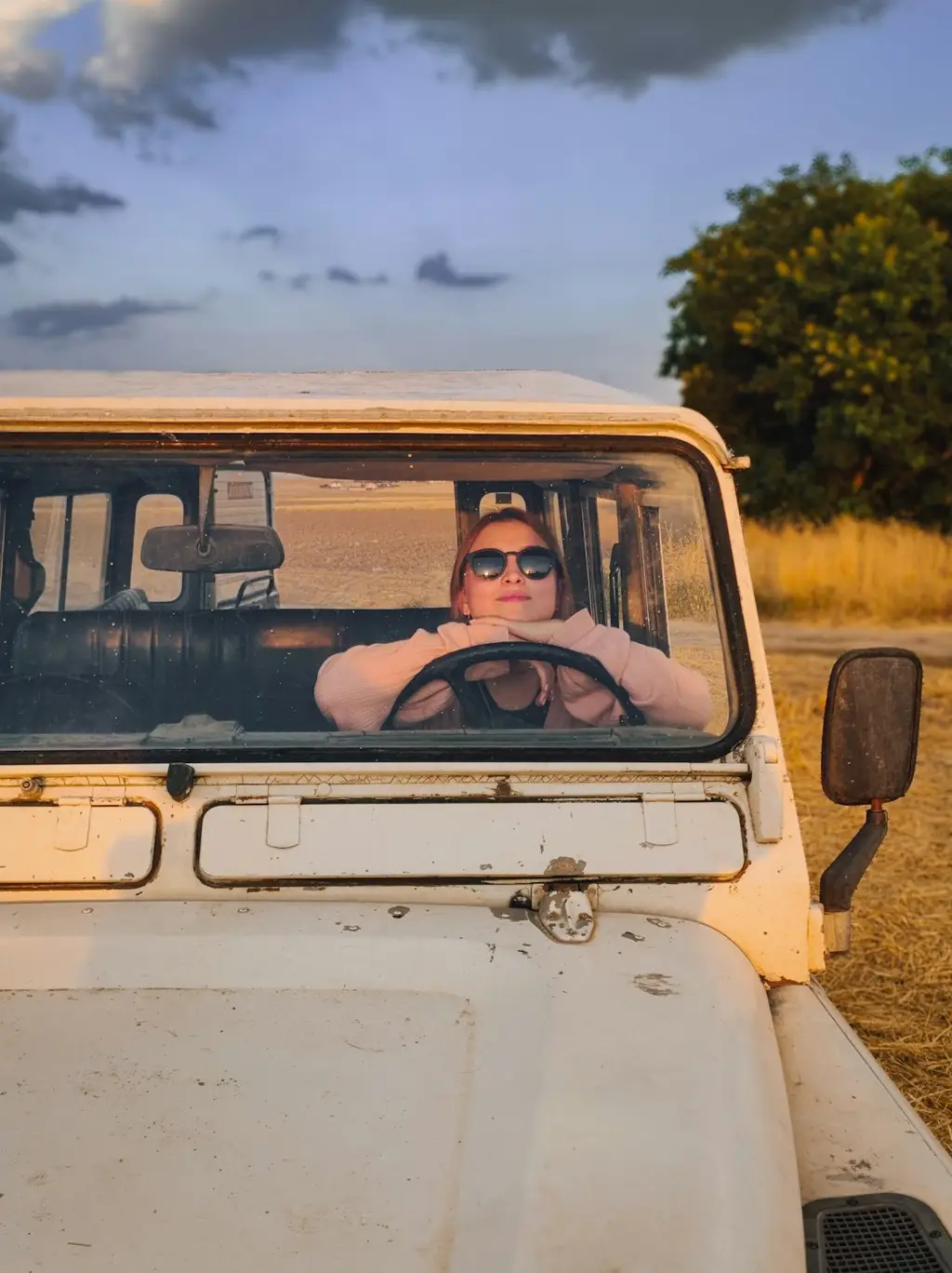 A woman sitting in the driver's seat of a white jeep